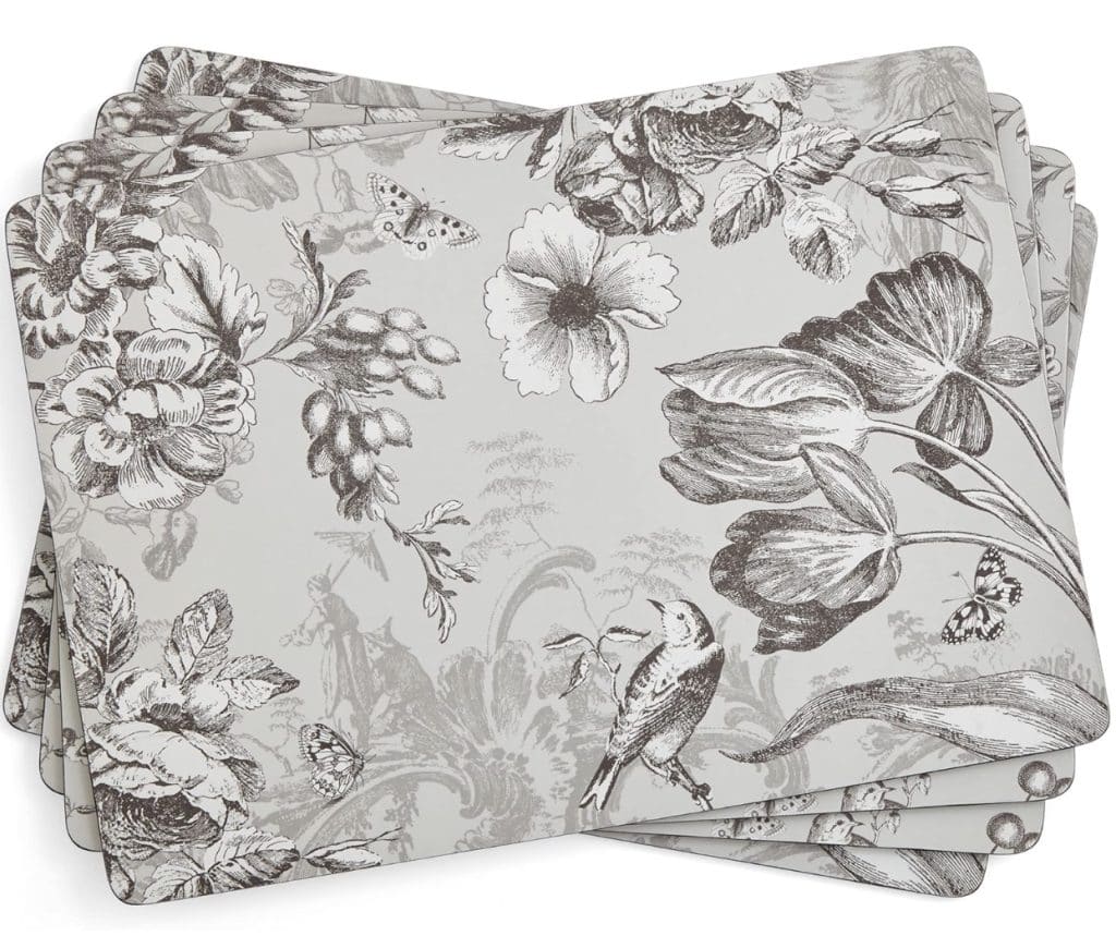 Four stacked easy corkboard placemats with a black-and-white botanical print featuring flowers, leaves, a bird, berries, and butterflies on a light background.